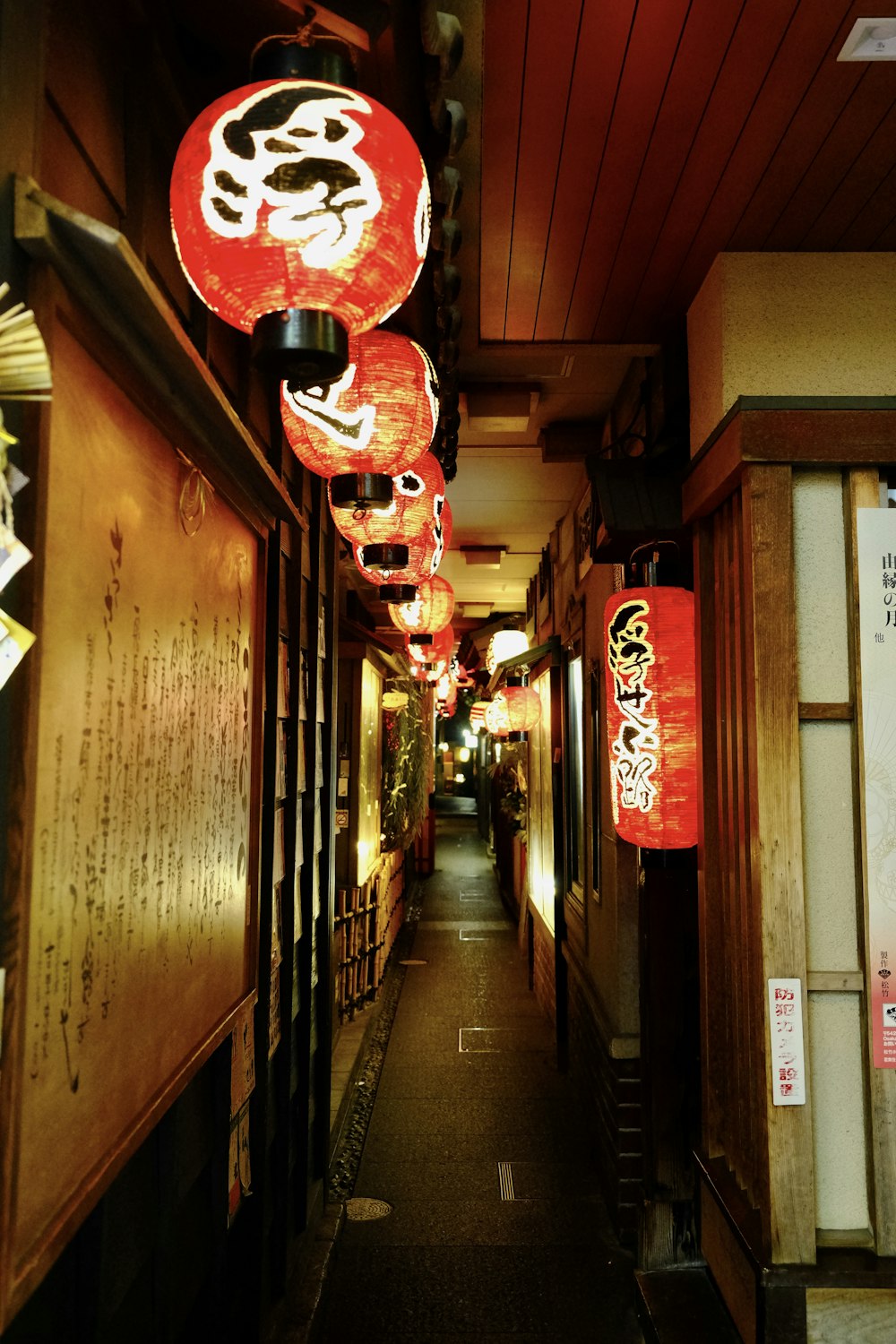 a narrow hallway with lanterns hanging from the ceiling