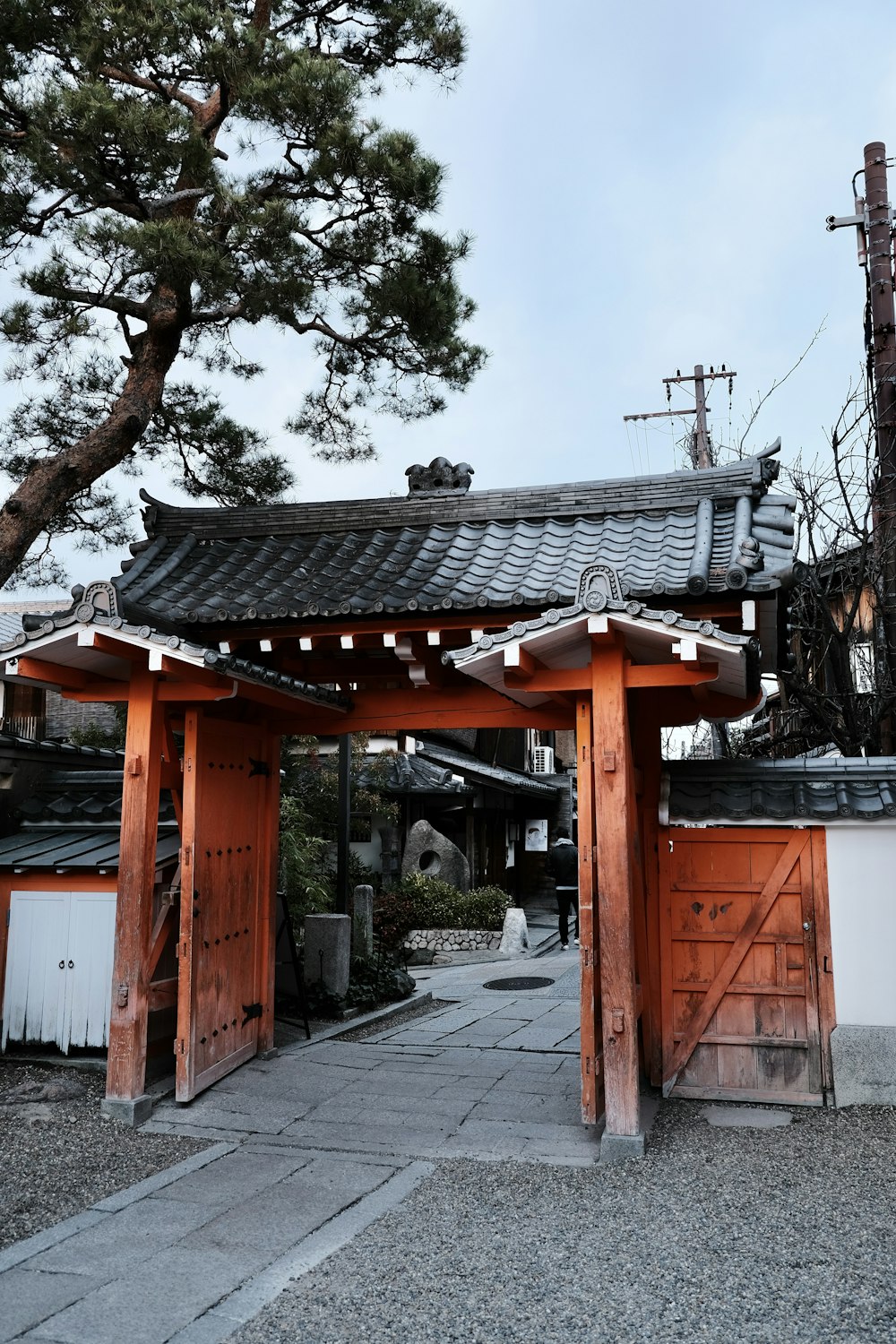 a wooden gate with a roof and a tree in the background