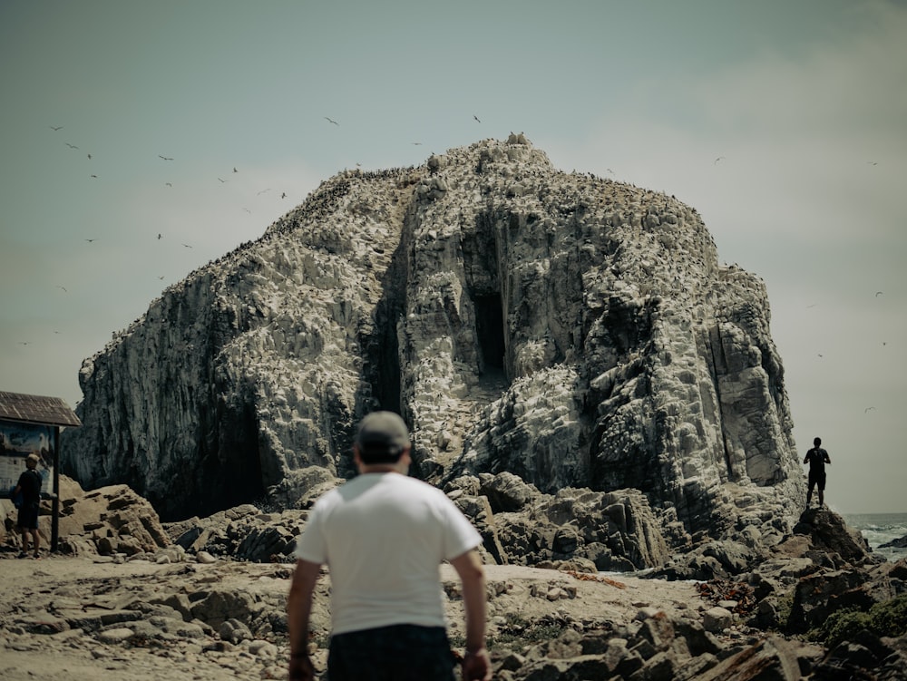 a man standing in front of a large rock formation