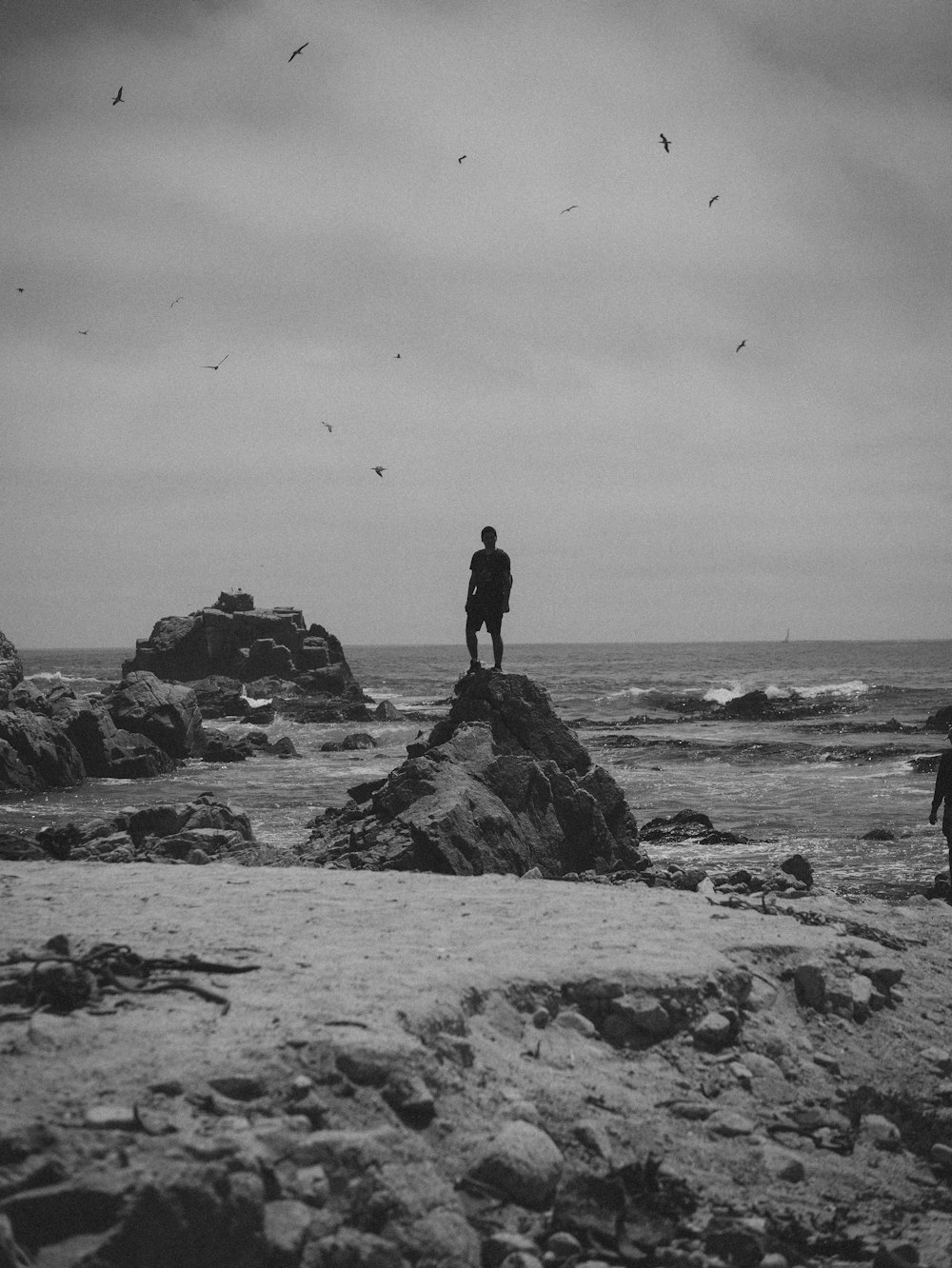 a couple of people standing on top of a rocky beach