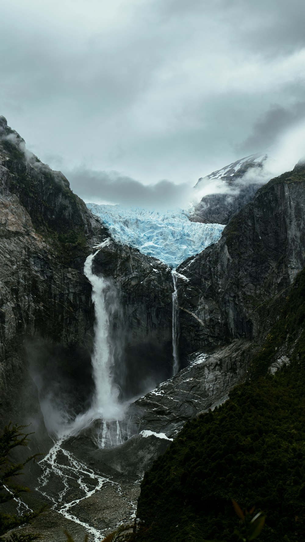 a waterfall with a glacier in the background