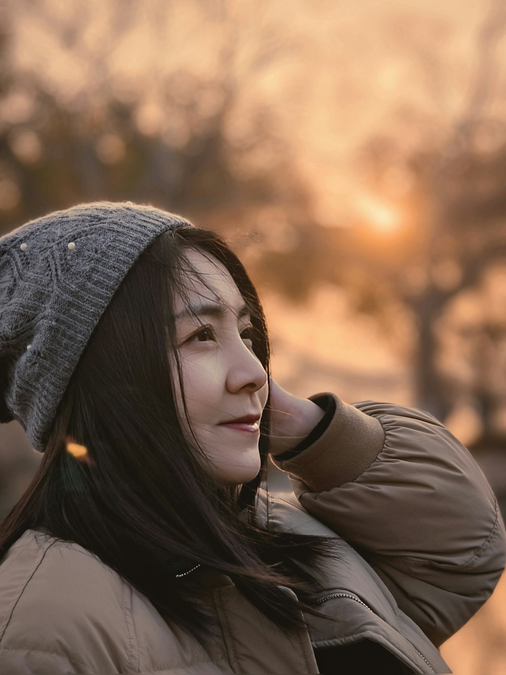 a woman talking on a cell phone while wearing a hat