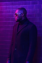 a man standing in front of a brick wall
