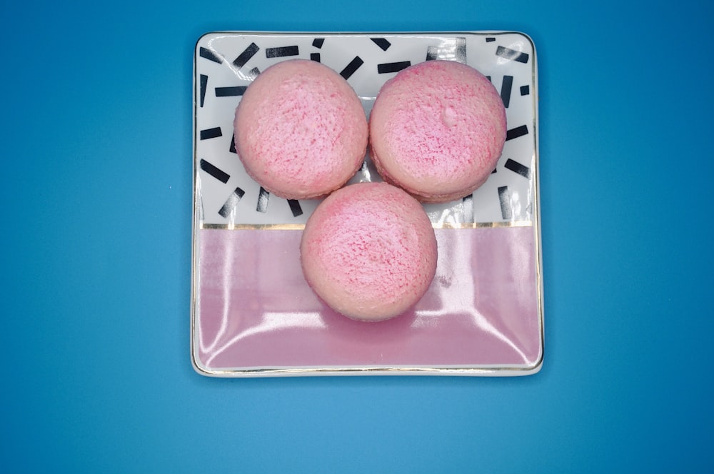 tre bombe da bagno rosa sedute su un piatto