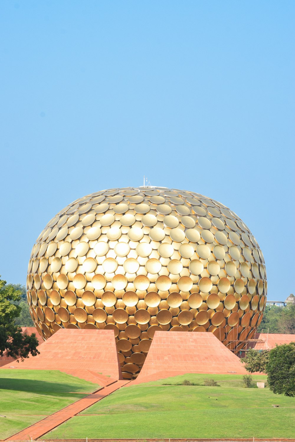 a large golden ball sitting on top of a lush green field