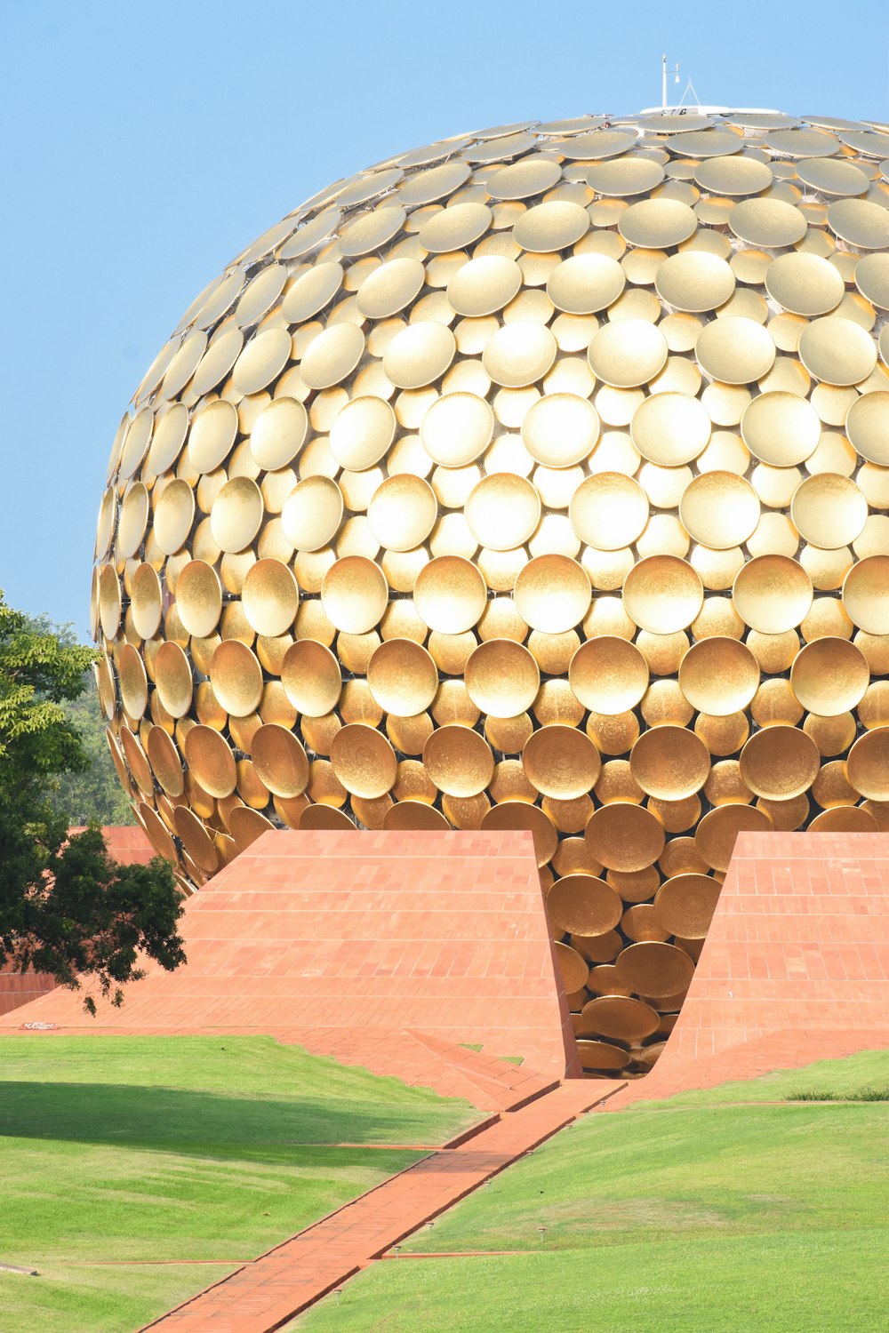 a large golden object sitting in the middle of a park