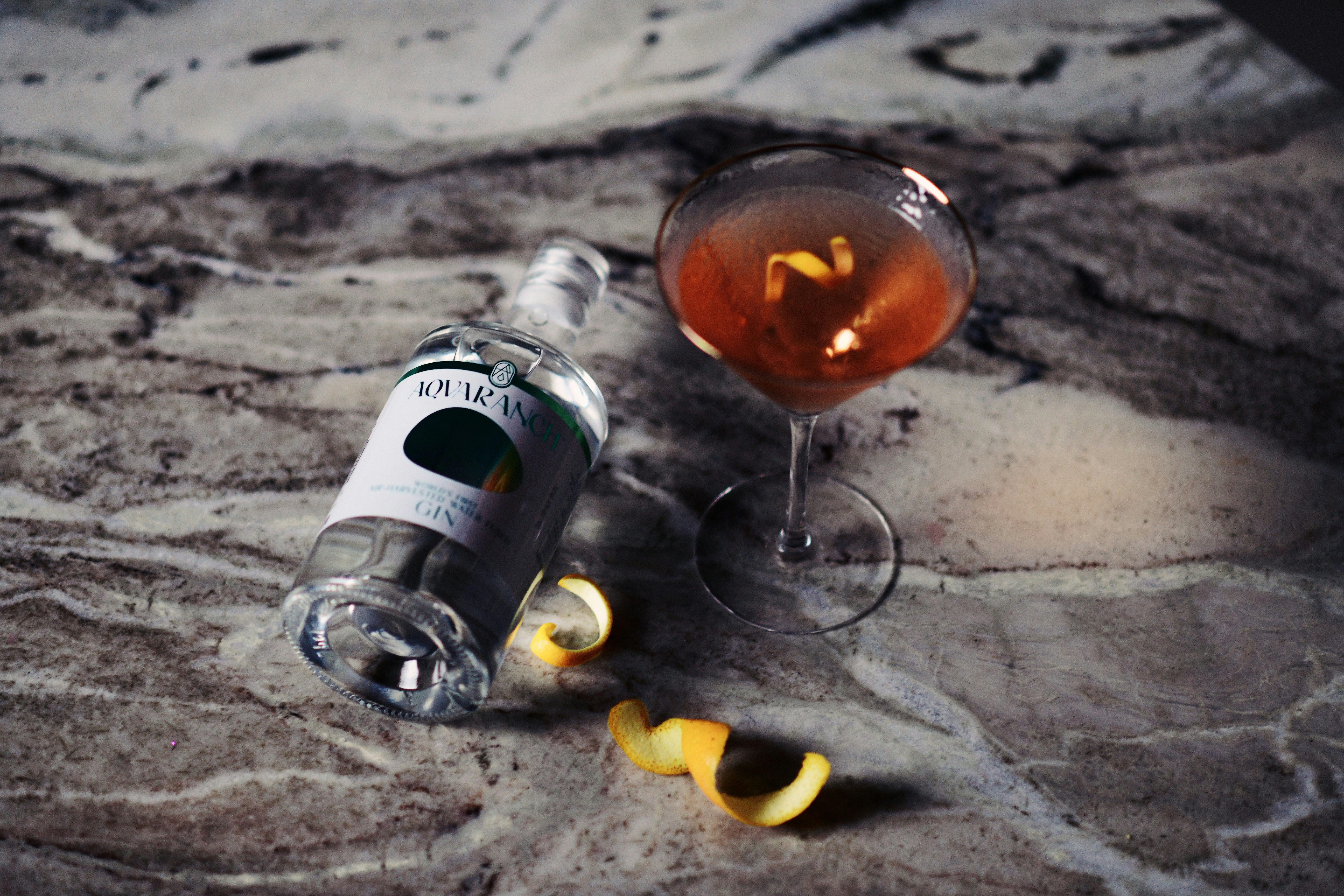 Dark cocktail on stone with citrus peel
