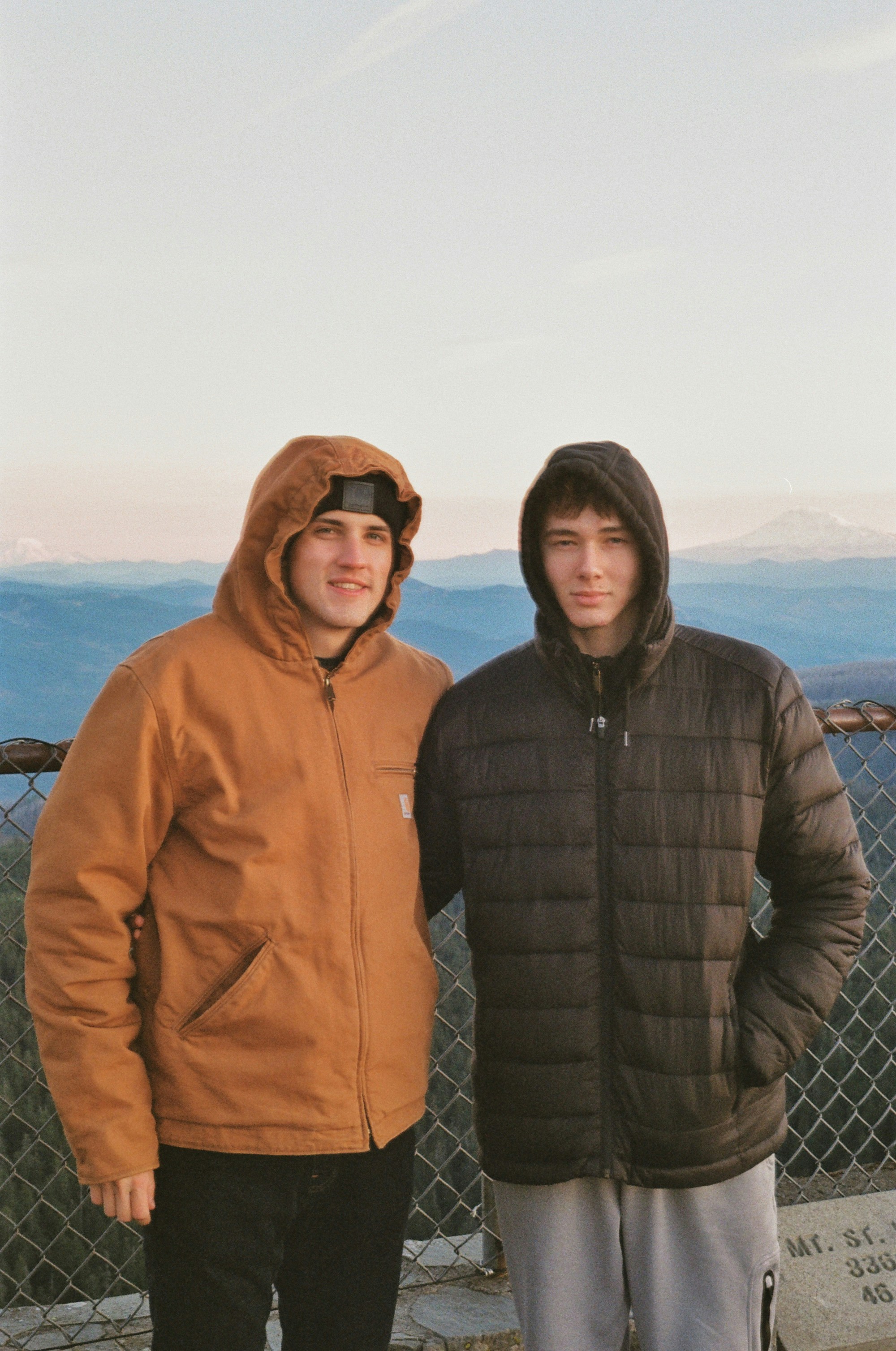 Two men standing next to each other in front of a fence photo – Free ...