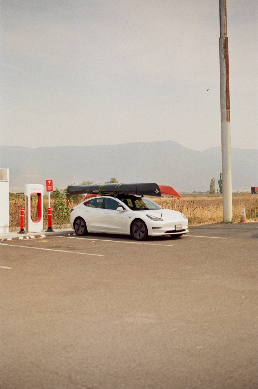 a white car parked in a parking lot next to a gas pump