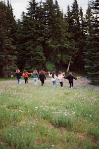 a group of people walking across a lush green field