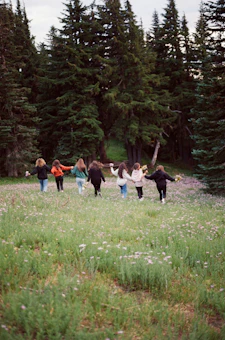 a group of people walking across a lush green field