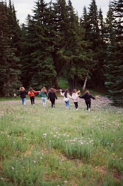 a group of people walking across a lush green field