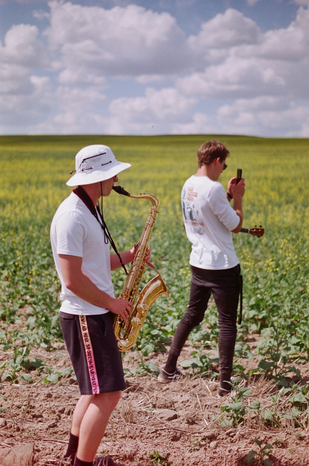 a couple of men standing in a field with a saxophone