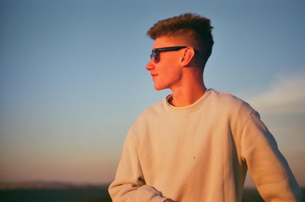 a young man wearing sunglasses standing on a hill