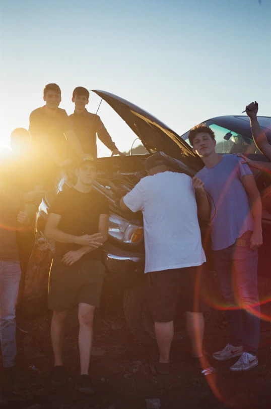 a group of people standing around a car
