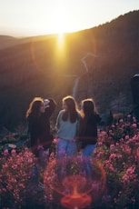 a group of women standing on top of a lush green hillside