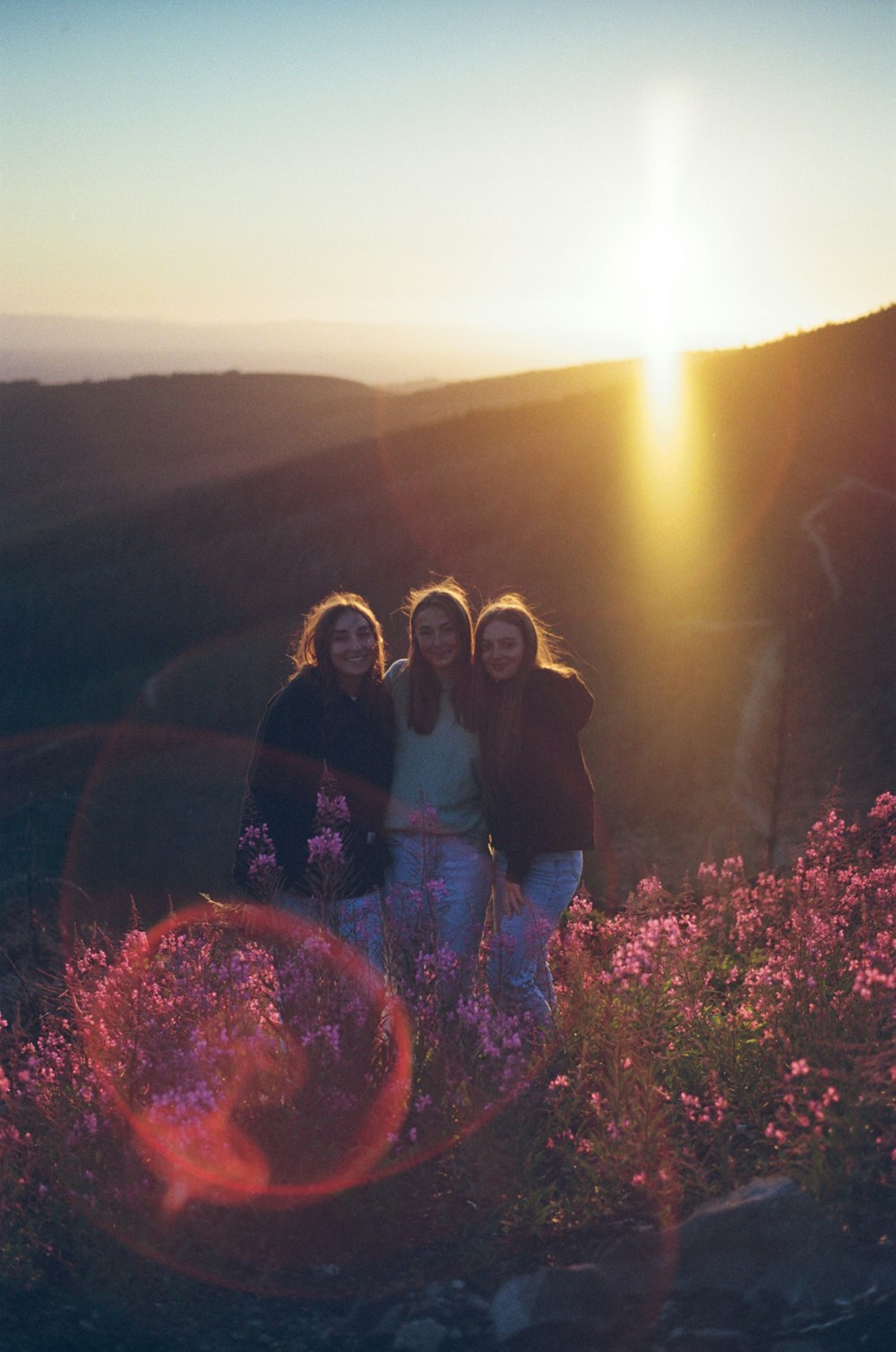 a group of women standing on top of a lush green hillside