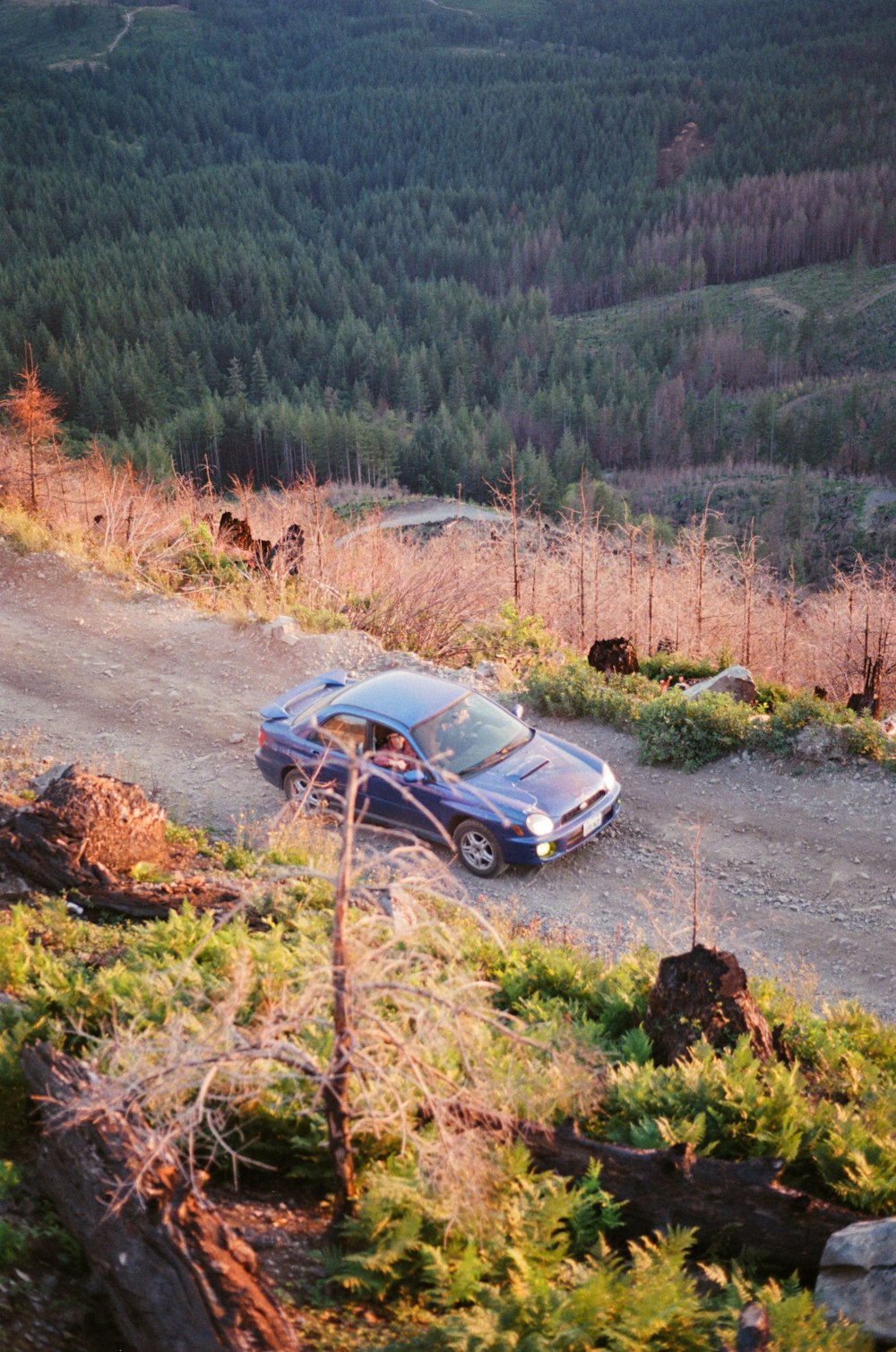 a car is parked on the side of a dirt road