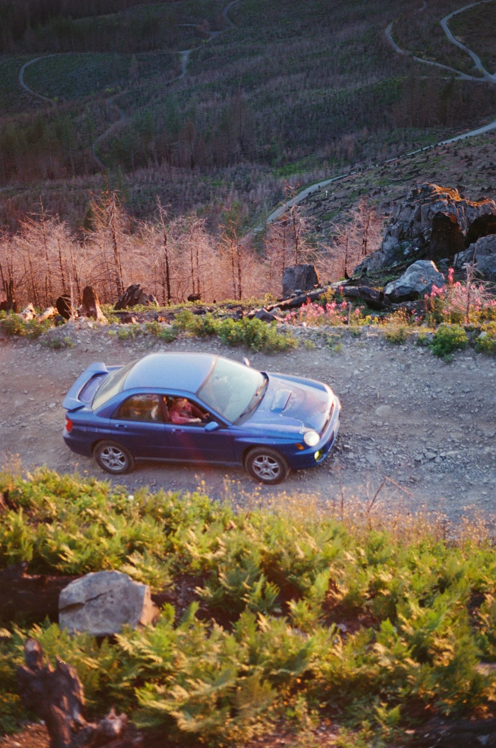 a blue car parked on a gravel road