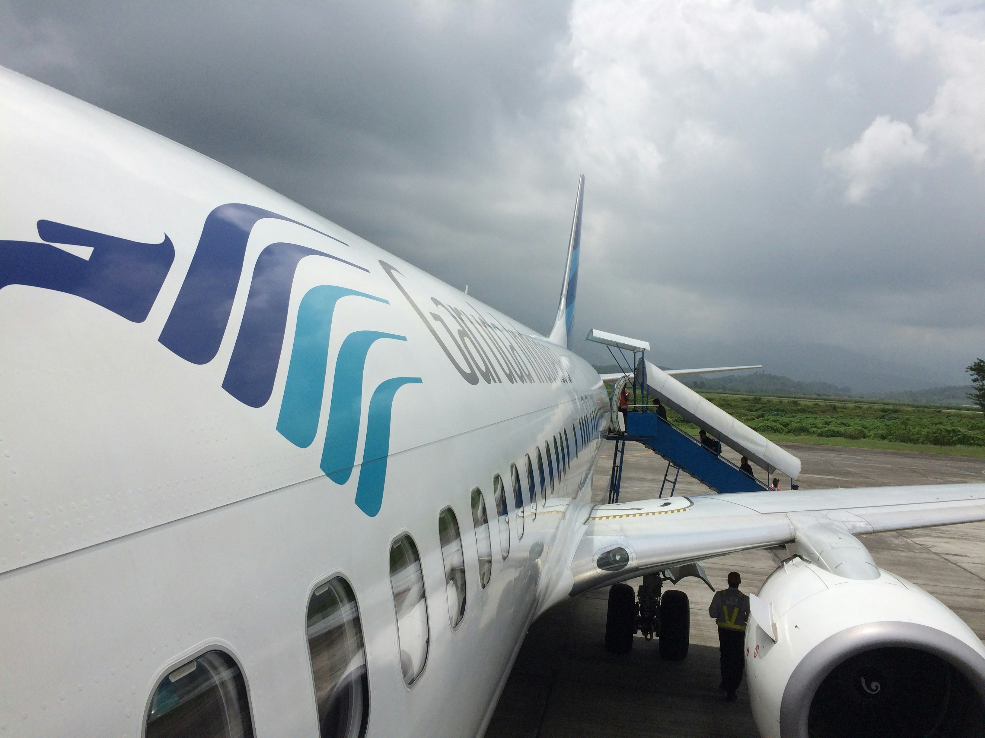 a large jetliner sitting on top of an airport tarmac, The Garuda Indonesia aircraft that touched down at the airport exemplifies the sophisticated elegance and elegance of aviation technology. This airplane, bearing the magnificent Garuda insignia on its tail, is a proud representation of Indonesia
