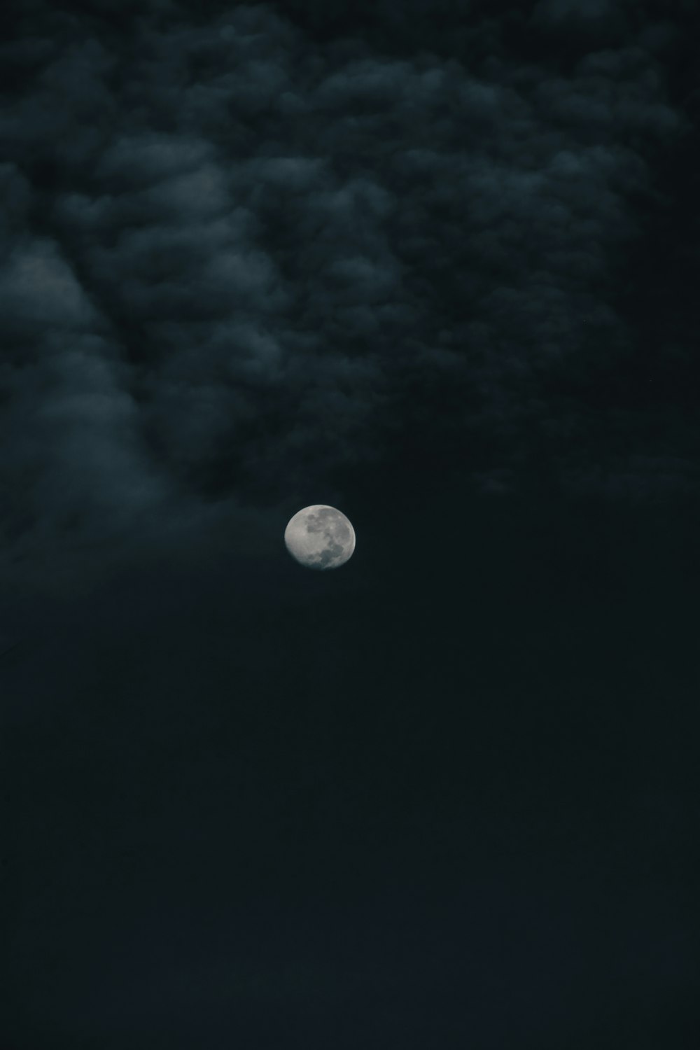 a full moon in a dark sky with clouds