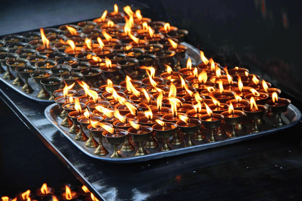 a tray filled with lots of lit candles