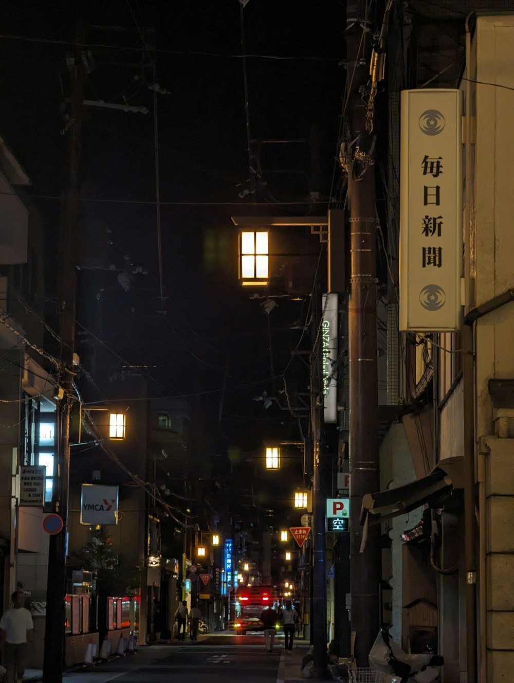 a city street at night with people walking on the sidewalk