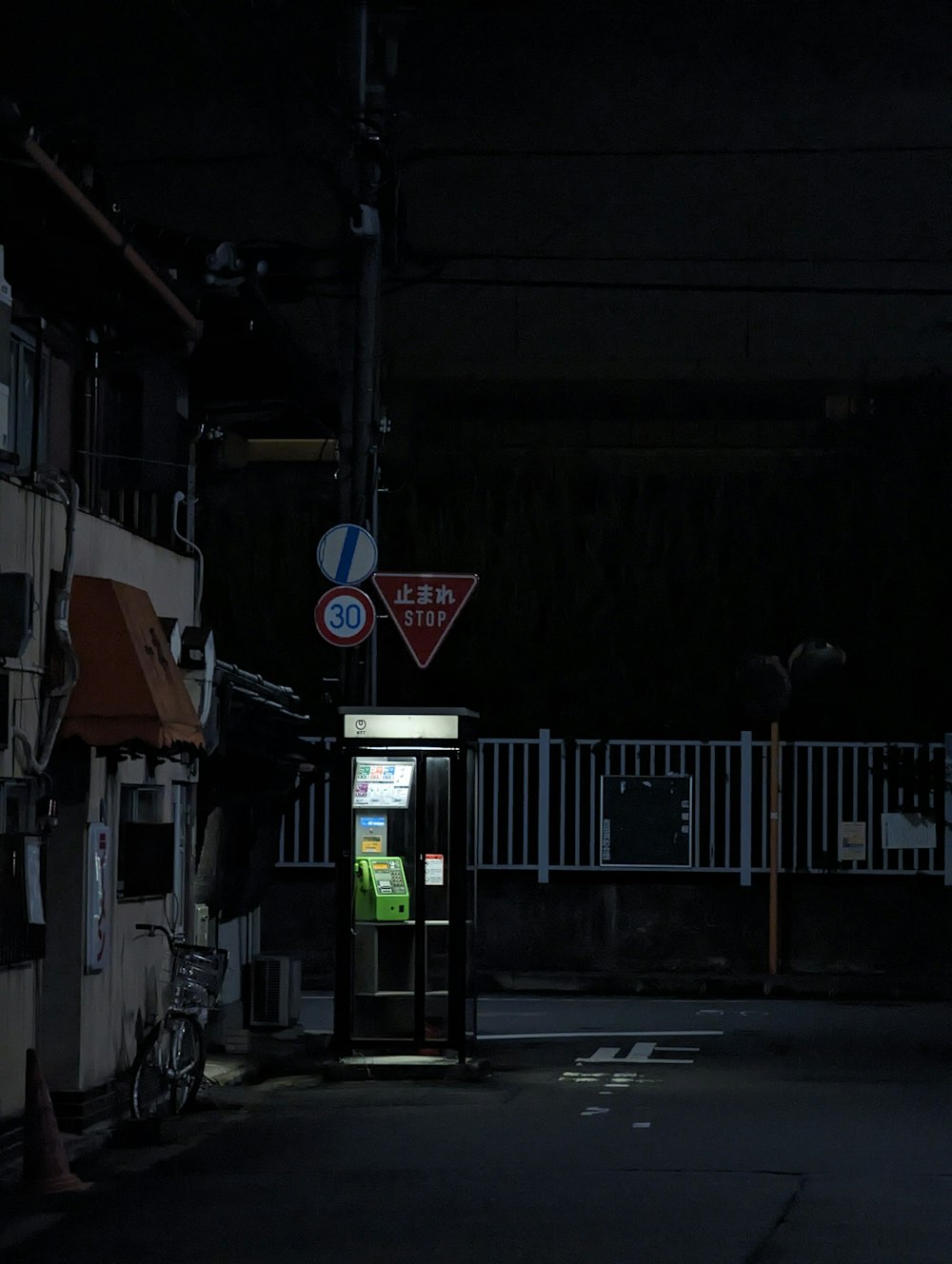 a dark street at night with a phone booth