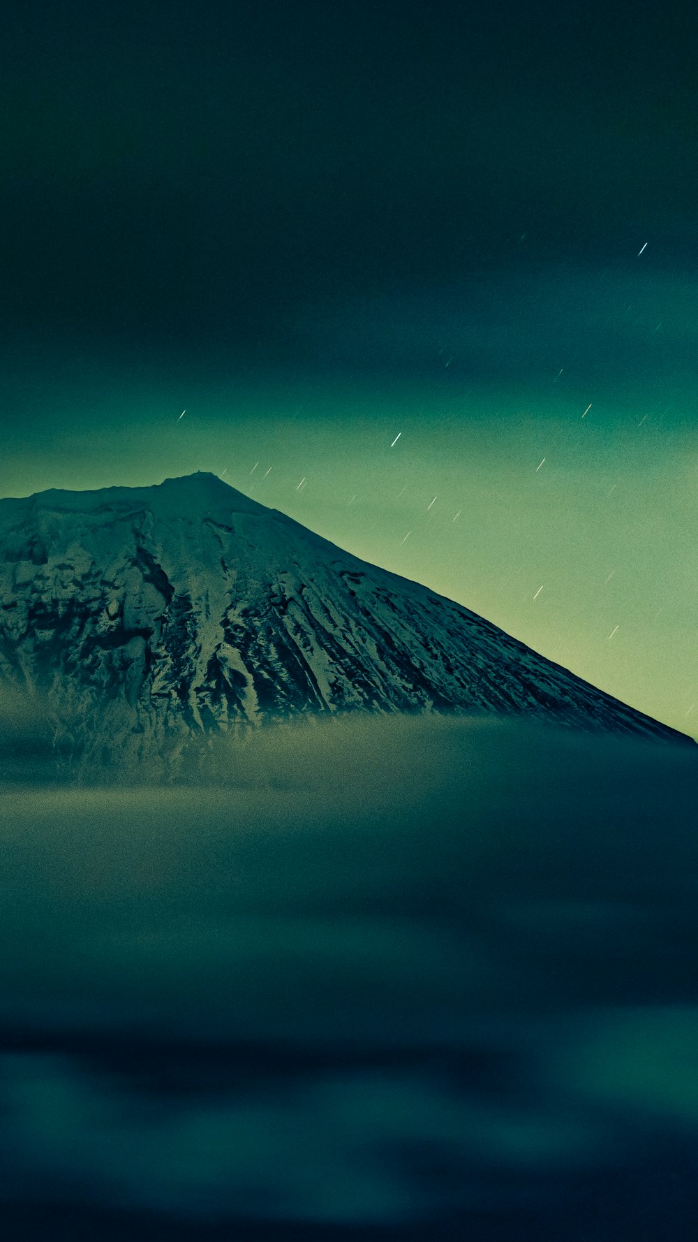 a mountain covered in snow under a cloudy sky