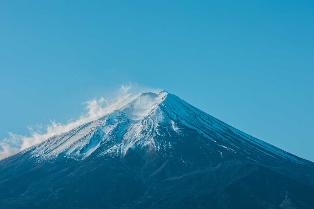 a very tall mountain covered in snow under a blue sky