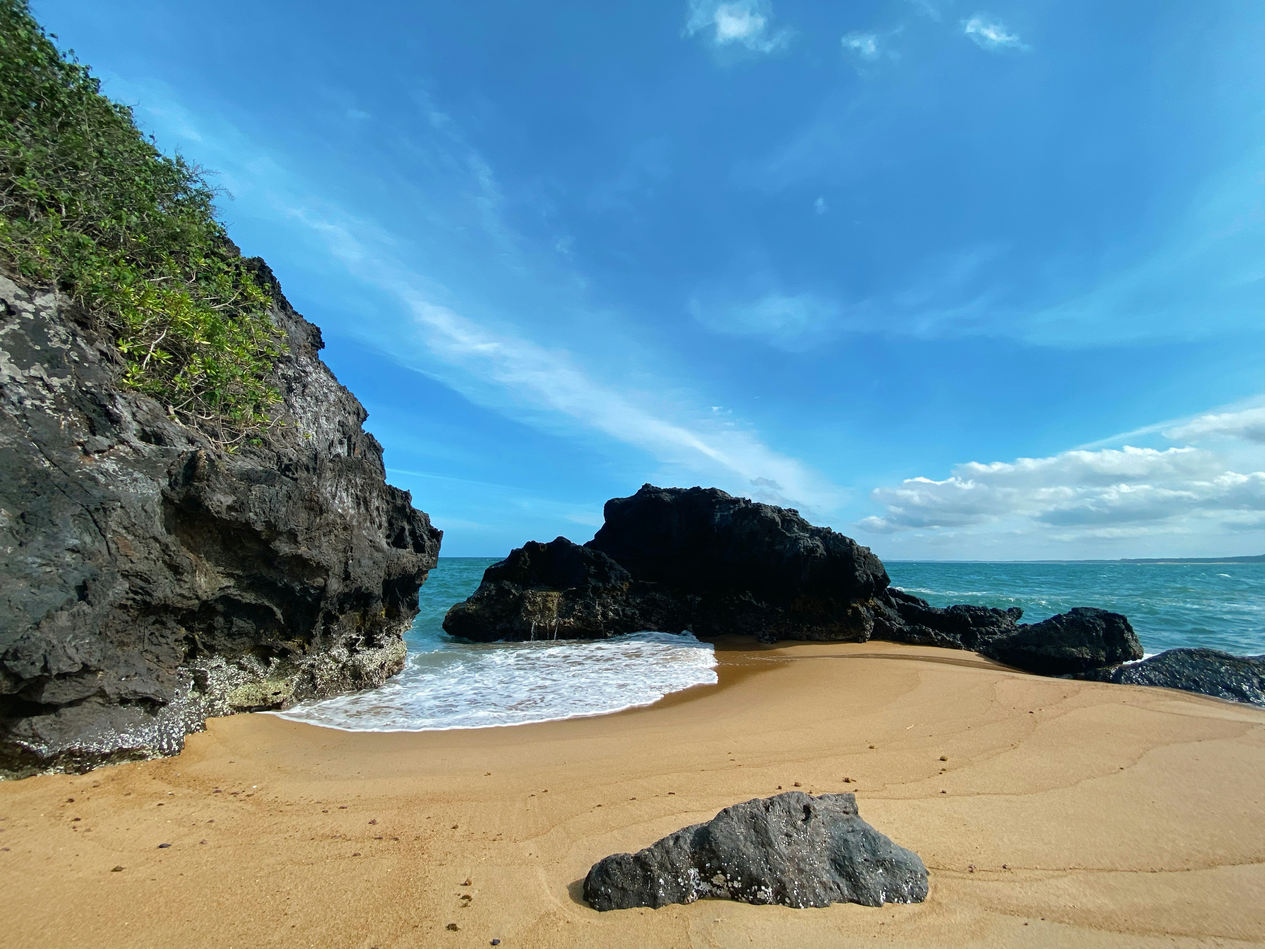 a sandy beach next to the ocean under a blue sky