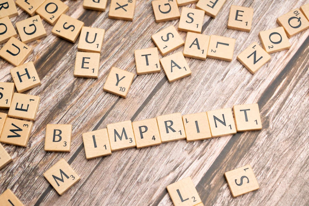 scrabble tiles spelling the word imprint on a wooden surface