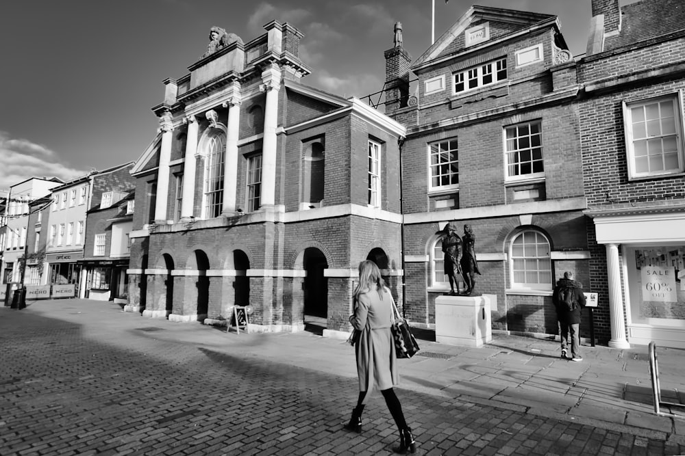 a black and white photo of a woman walking down the street