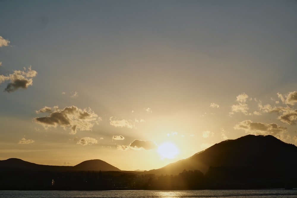 the sun is setting over a mountain range