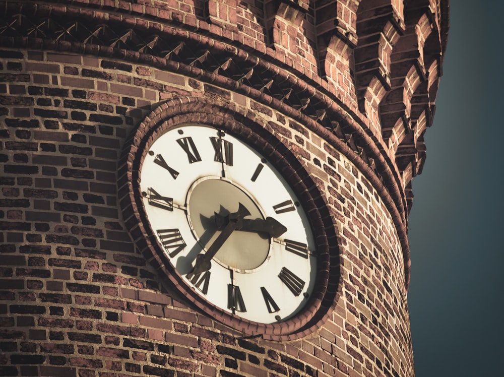eine Uhr auf einem gemauerten Turm mit römischen Ziffern