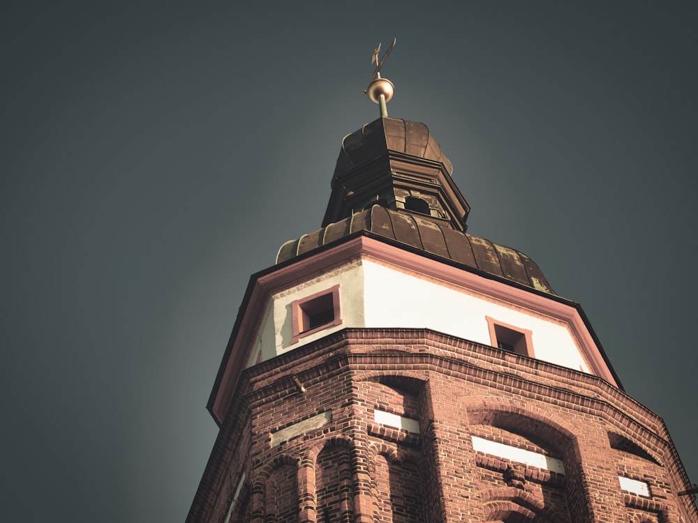 a tall brick tower with a weather vane on top