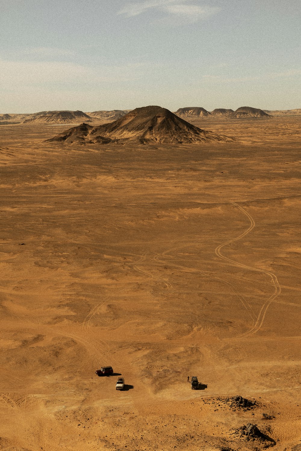 a dirt field with a hill in the distance