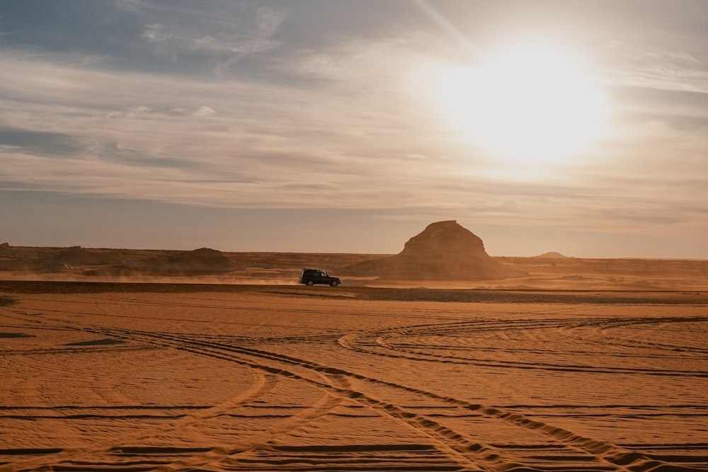 a truck driving through the desert at sunset