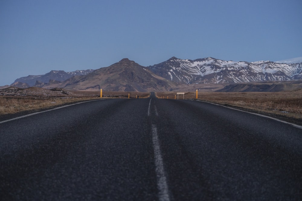 an empty road with mountains in the background