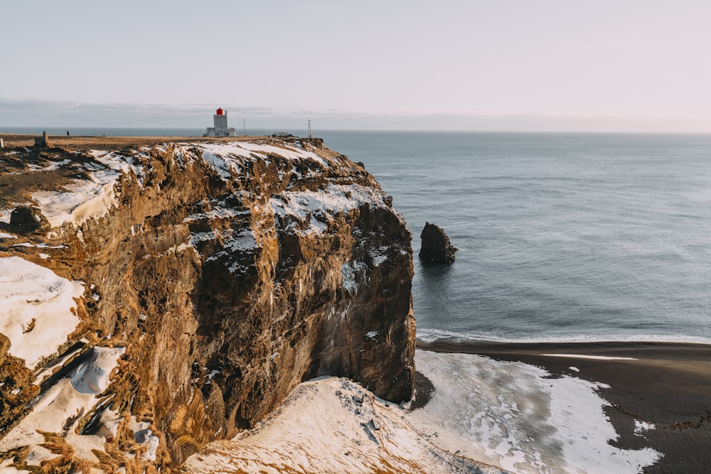 a person standing on top of a cliff next to the ocean