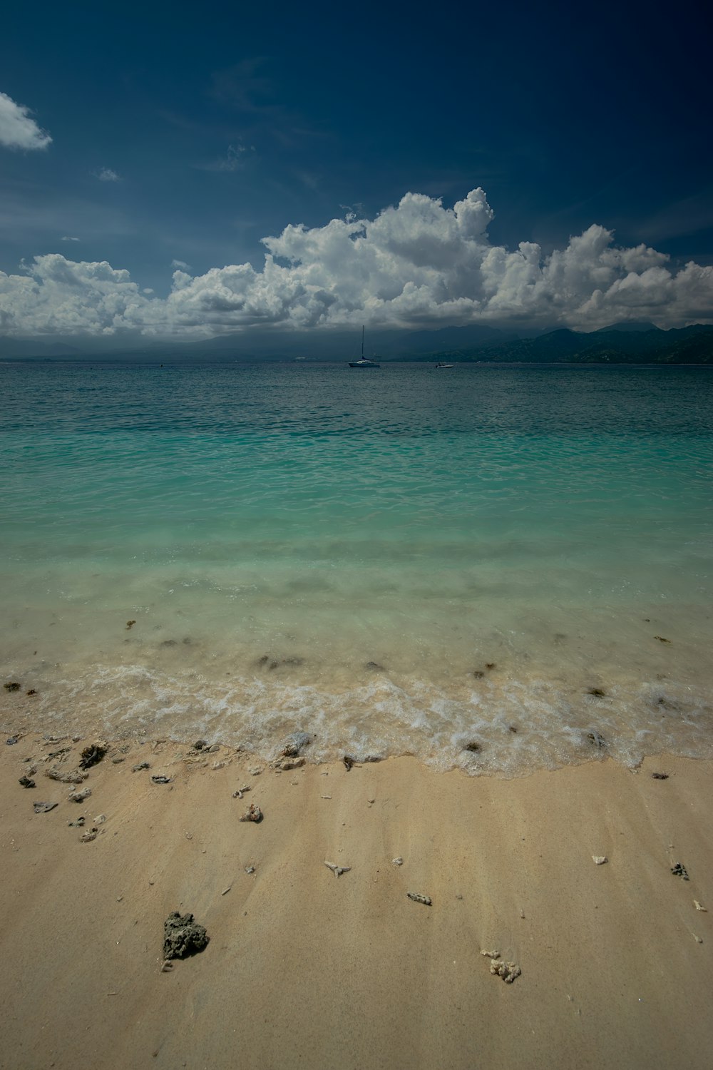 a sandy beach with clear blue water under a cloudy sky