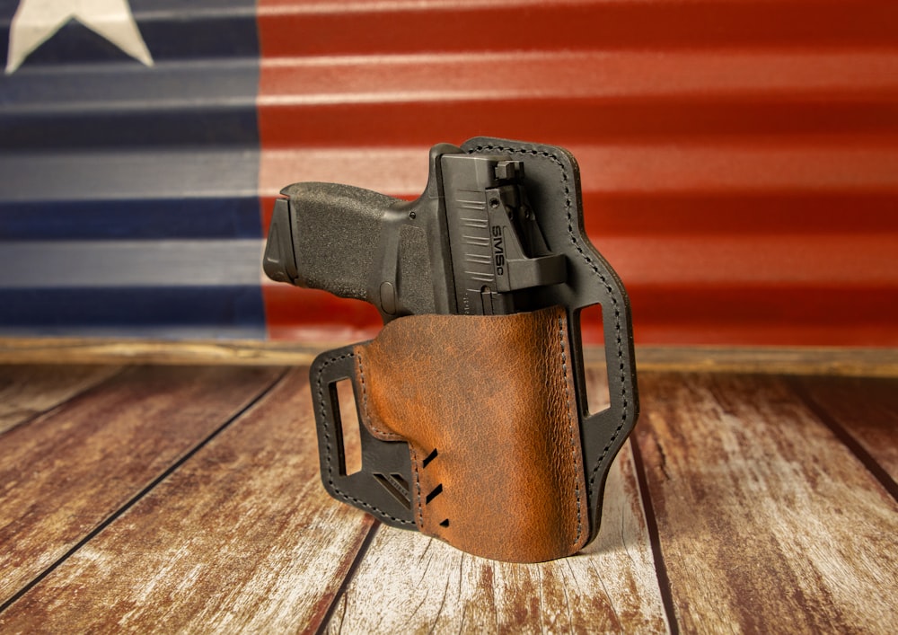 a leather holster on a wooden table with a flag in the background