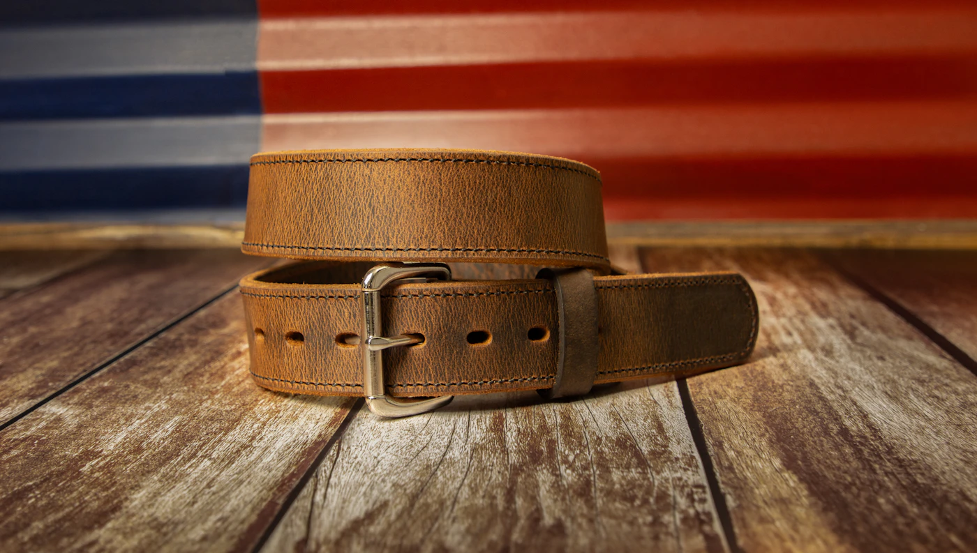 Ceinture en cuir marron posée sur un plancher en bois