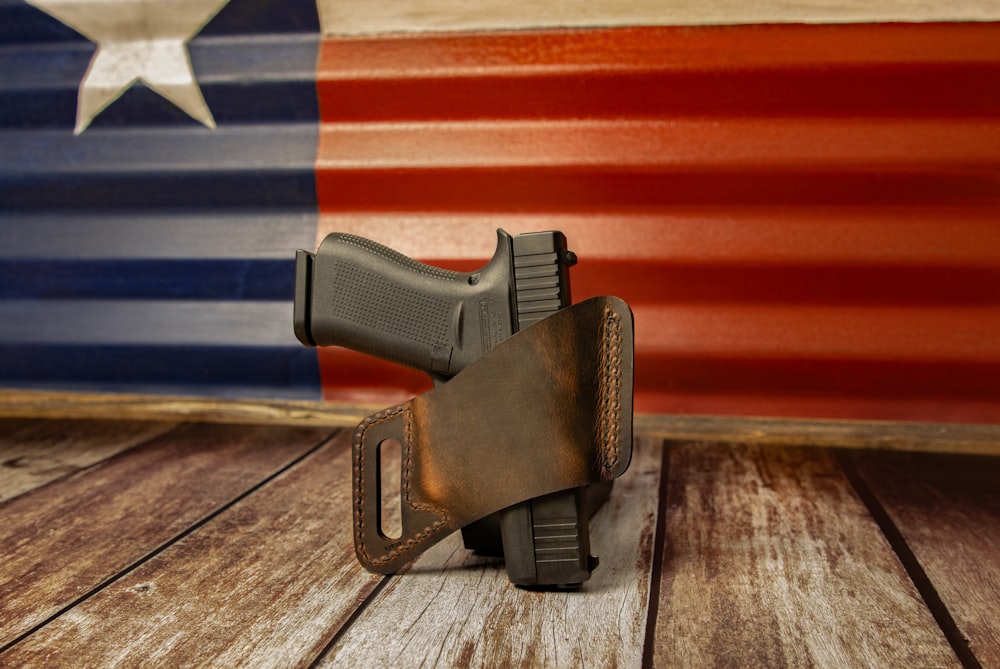 a leather holster on a wooden surface with the american flag in the background