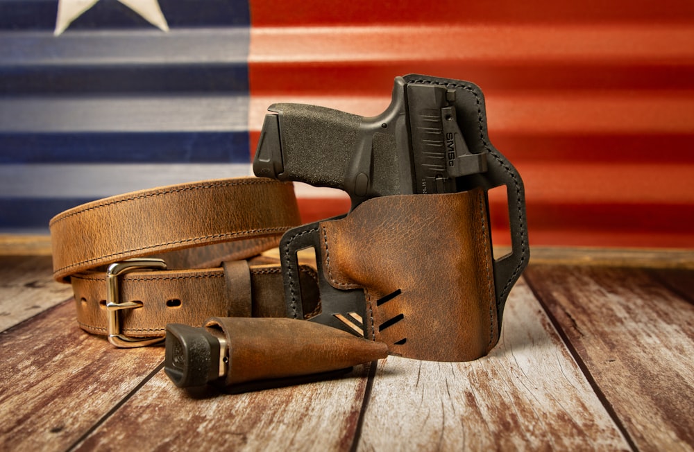 a leather belt with a gun and a holster on a wooden table