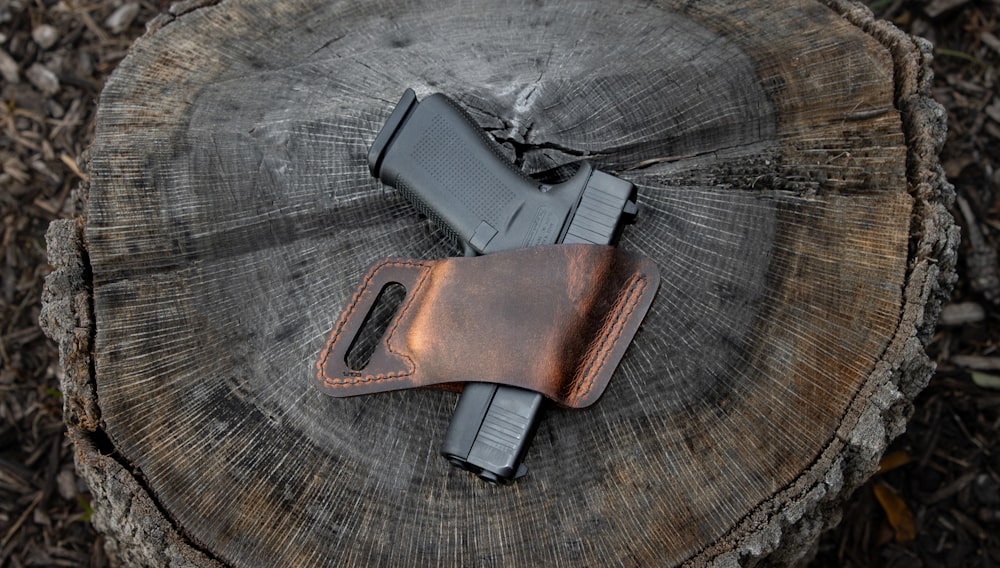 a leather sheath with a gun on top of a piece of wood