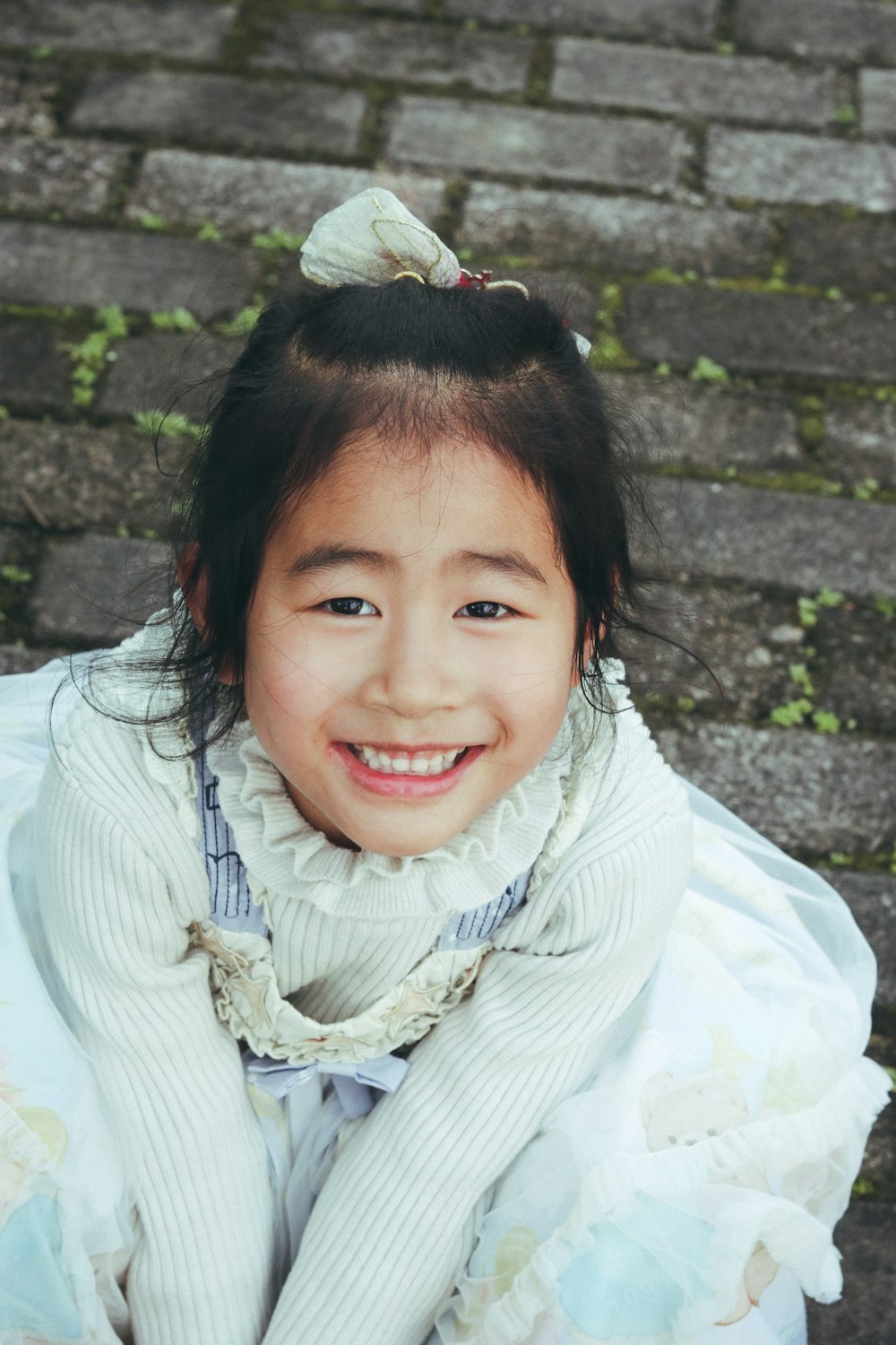 a little girl sitting on the ground smiling