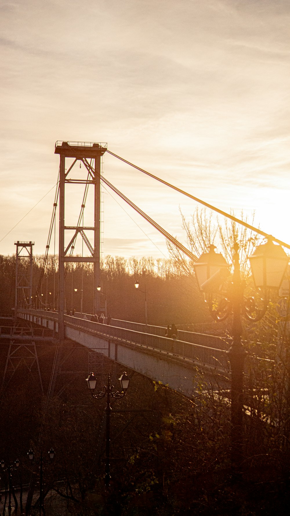 the sun is setting on a bridge over a river