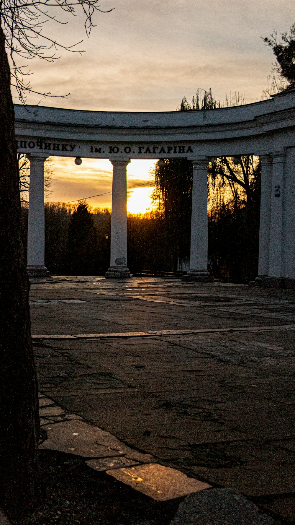 the sun is setting behind a white arch