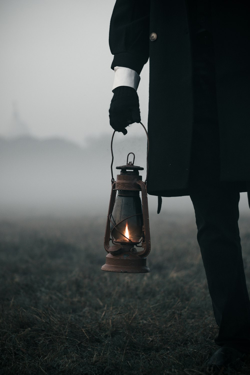 a person in a black coat holding a lantern